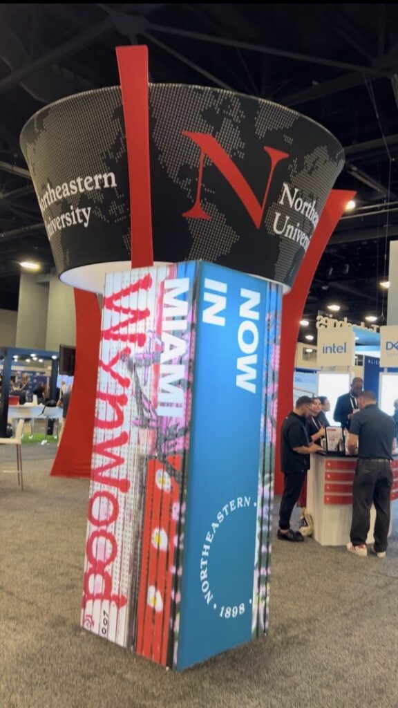 Custom Northeastern University trade show tower display with printed graphics on the exhibit floor.